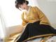 A woman in a yellow and black hanbok sitting on a bed.