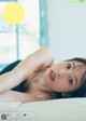 A woman laying on top of a bed next to a window.