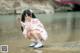 A woman in a pink kimono is sitting in the water.