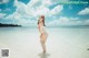 A woman in a white bathing suit standing in the water.