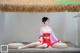 A woman in a red dress sitting on a wooden platform.