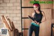 A woman in a black sports bra top and black leggings holding a yoga mat.