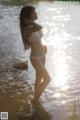 A woman in a white bikini standing in the water.