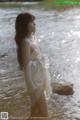 A woman in a white dress standing in the water.