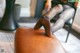 A woman sitting on top of a brown leather ottoman.