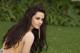 A woman with long brown hair sitting in the grass.