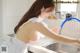 A woman in a white dress is washing her hands in the kitchen sink.