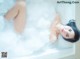 A woman laying in a bathtub filled with foam.